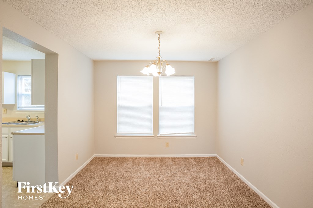 A room with a carpeted floor and a window with blinds.