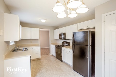 A kitchen with a black fridge and white cabinets.