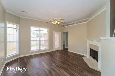 A spacious living room with wood flooring and a fireplace.