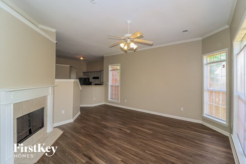 A spacious living room with a fireplace and a ceiling fan.