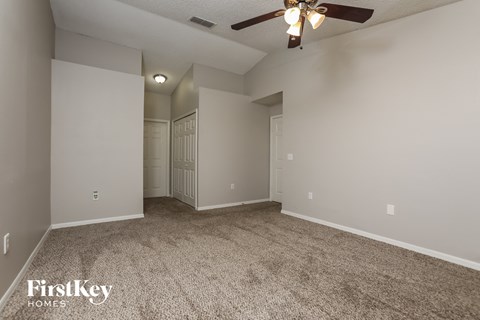 a spacious living room with carpet and a ceiling fan