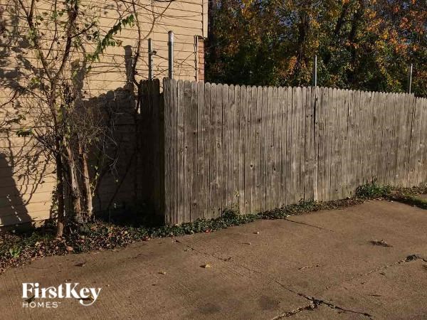 A wooden fence in front of a house with trees in the background.