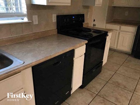 A kitchen with a black stove top oven and white cabinets.