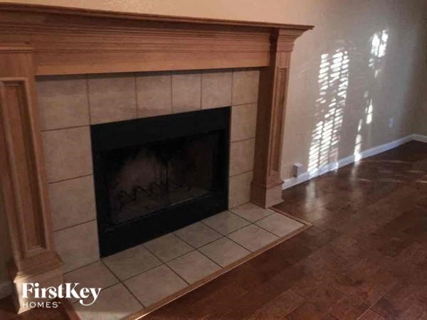 A fireplace with a wooden frame and a black grate is in a room with wooden flooring.