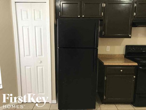 a kitchen with a black refrigerator and black cabinets