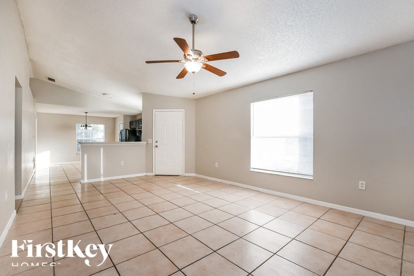A spacious room with a ceiling fan and tiled flooring.