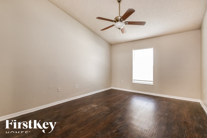 A room with a ceiling fan and wooden flooring.