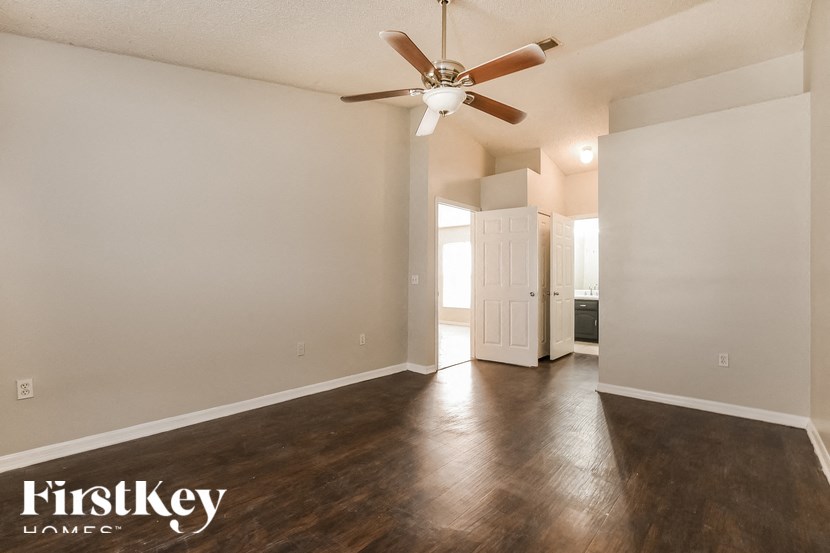 A spacious room with a ceiling fan and wooden flooring.