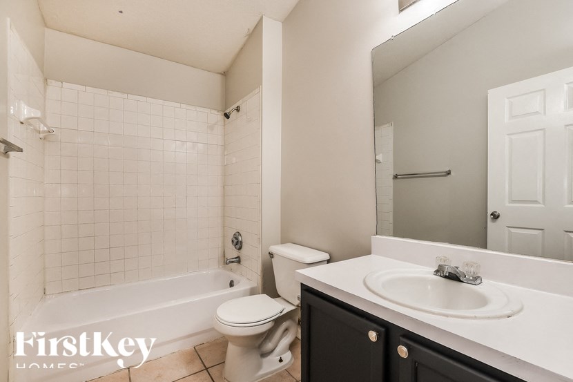 A white bathroom with a black cabinet and a white toilet.
