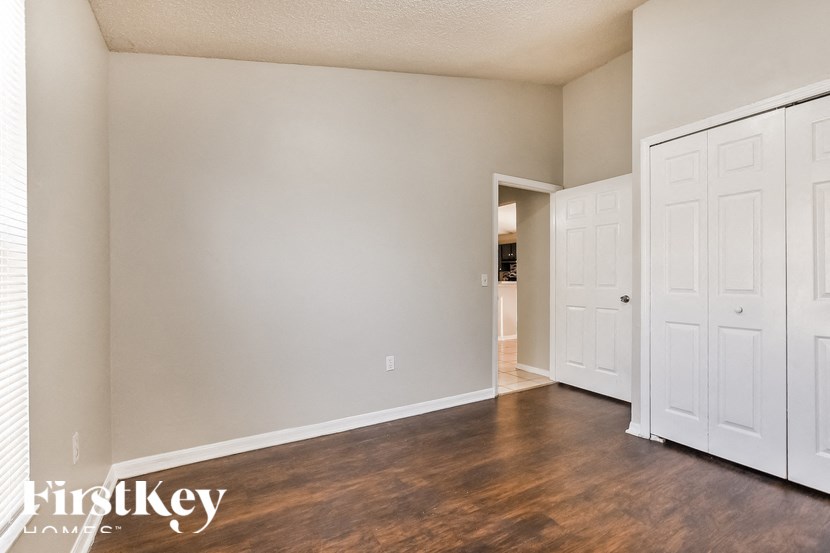 A room with wooden floors and white walls, with a door on the right side.