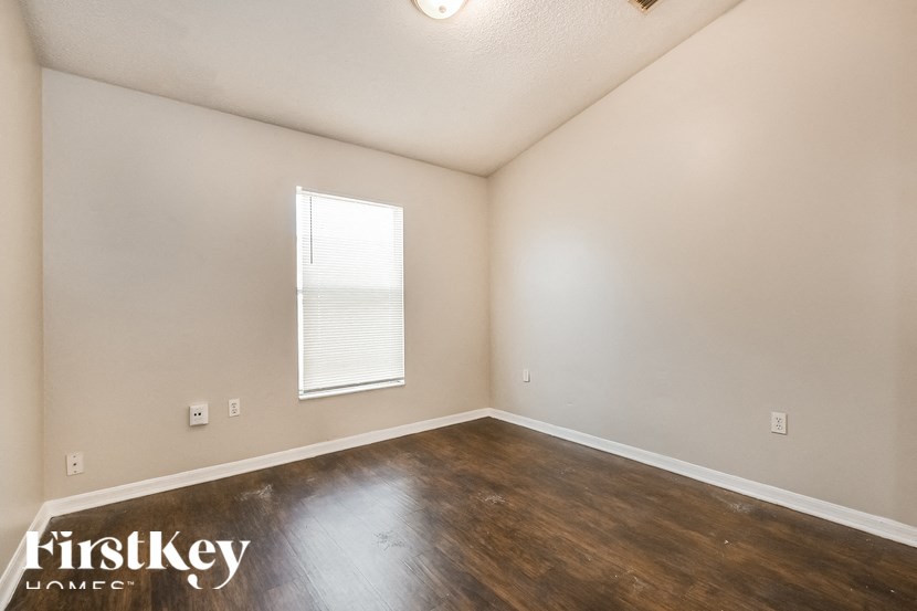 A room with wooden floors and a window with blinds.