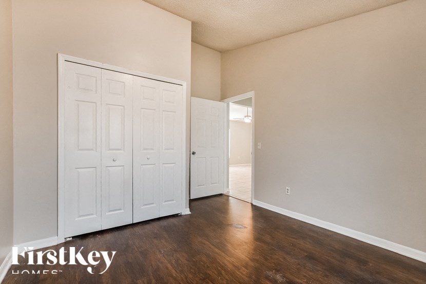 A room with a white door and wooden flooring.