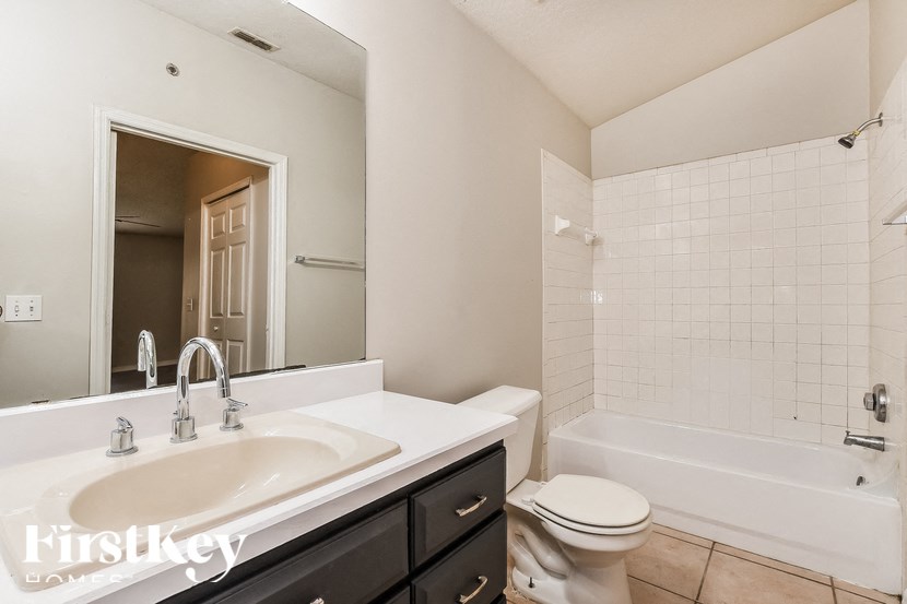 A white sink with a brownish bowl is in a bathroom with a white toilet and a white bathtub.