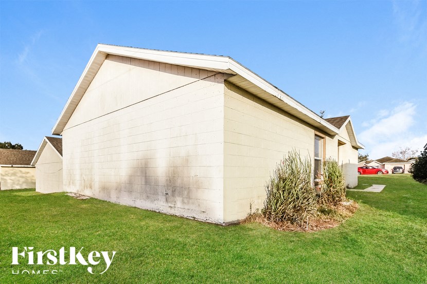 A small, beige house with a grassy front yard.