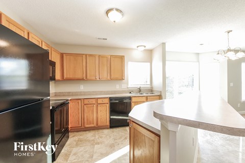 A kitchen with wooden cabinets and a black fridge.