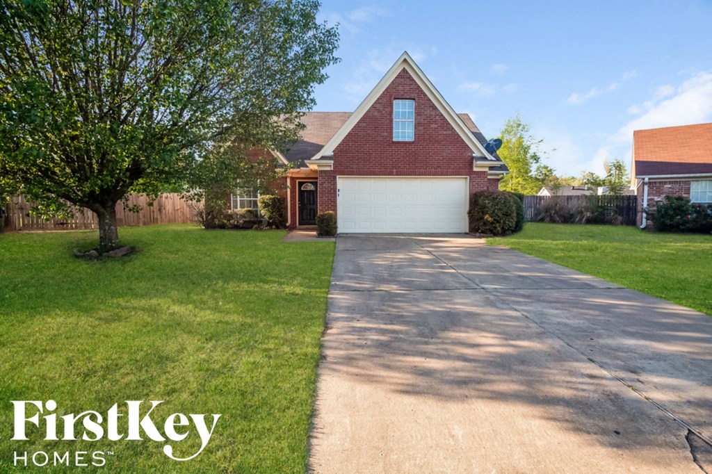 A house with a driveway and a tree in front of it.