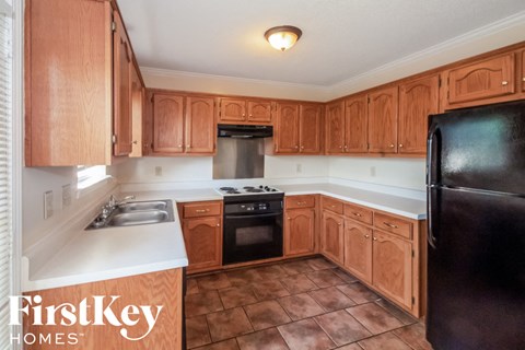 A kitchen with wooden cabinets and a black refrigerator.