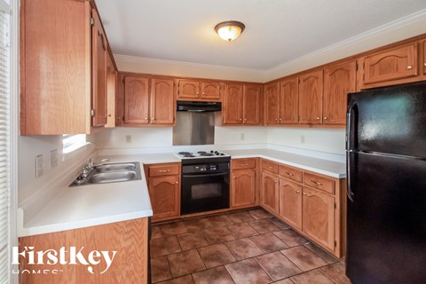 A kitchen with wooden cabinets and a black refrigerator.