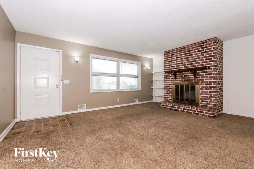the living room has a brick fireplace and carpeted flooring