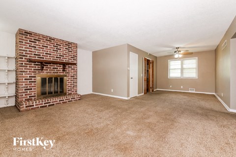 a living room with a brick fireplace and a carpeted floor