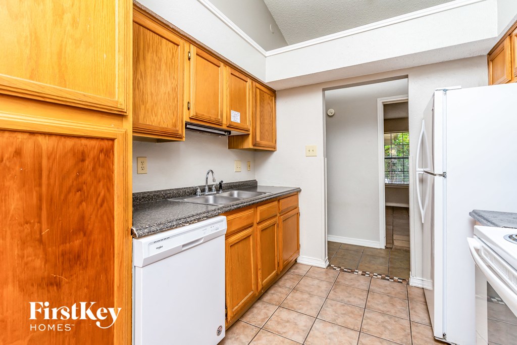 a kitchen with wooden cabinets and white appliances and a sink