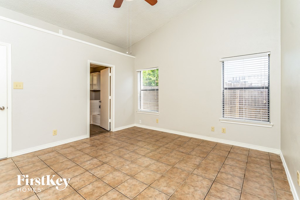 an empty living room with tile flooring and a door to the bathroom