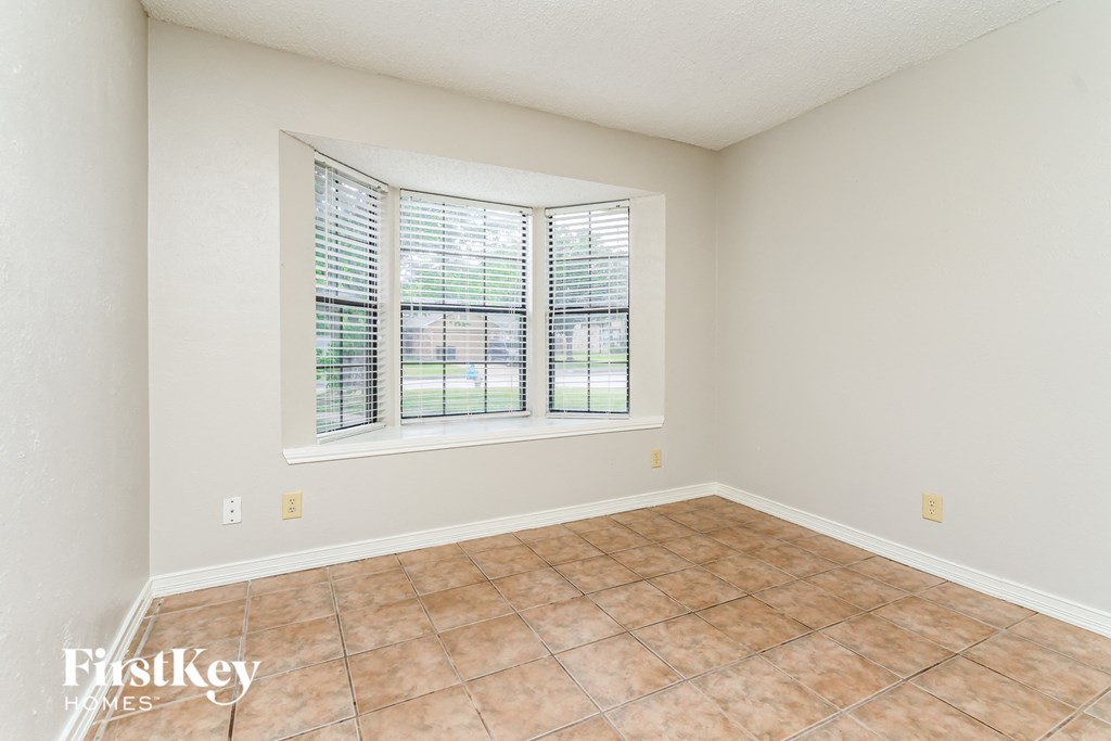 an empty living room with a large window and tiled floors