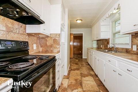 A kitchen with a black stove top oven and white cabinets.