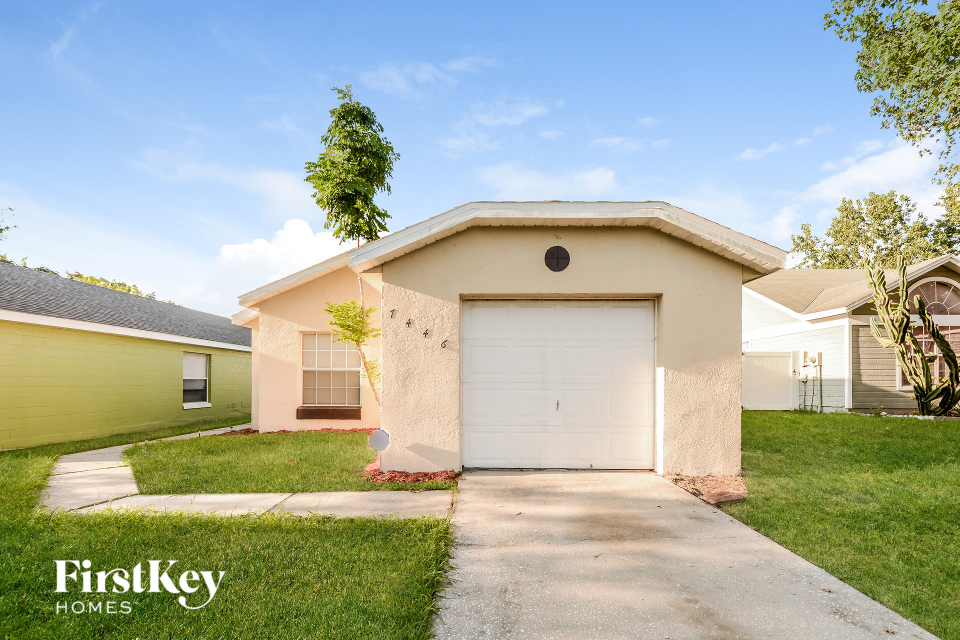A small house with a white garage door is for sale.