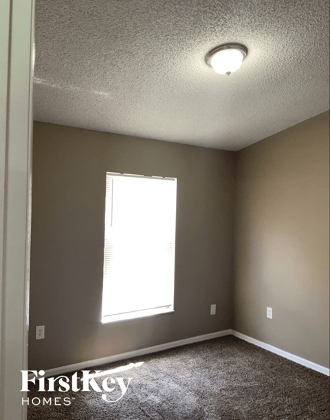 A room with a window and a carpet on the floor.