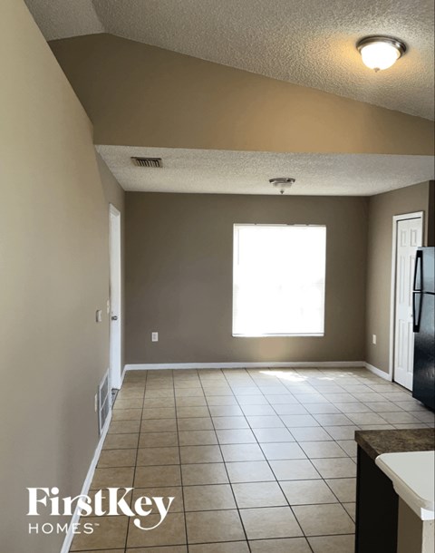A kitchen with a tile floor and a refrigerator.