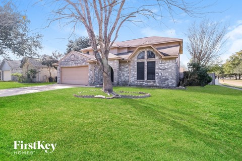 a stone house with a tree in the front yard