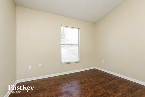 a bedroom with wood flooring and a window