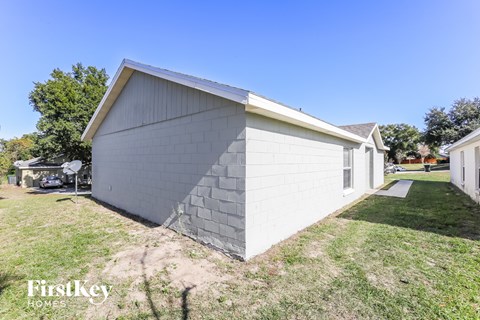 a small white building with a gray roof and a driveway