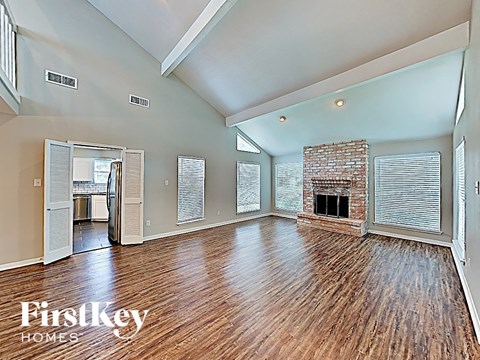 an open living room with a brick fireplace and wood floors