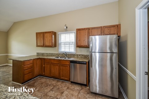 A kitchen with wooden cabinets and a stainless steel refrigerator.