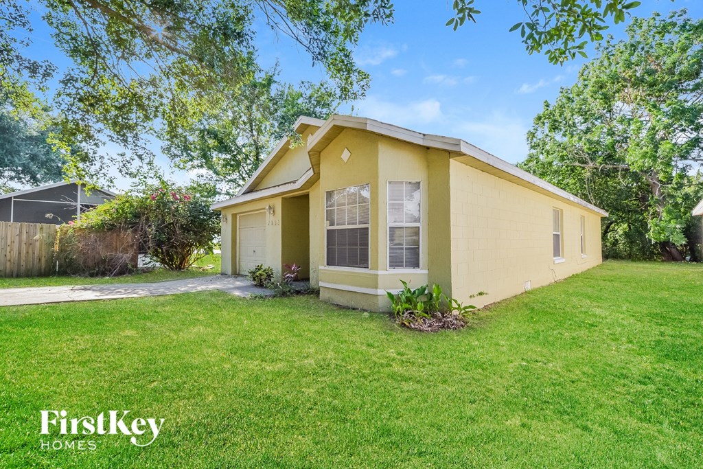 A yellow house with a green lawn in front of it.