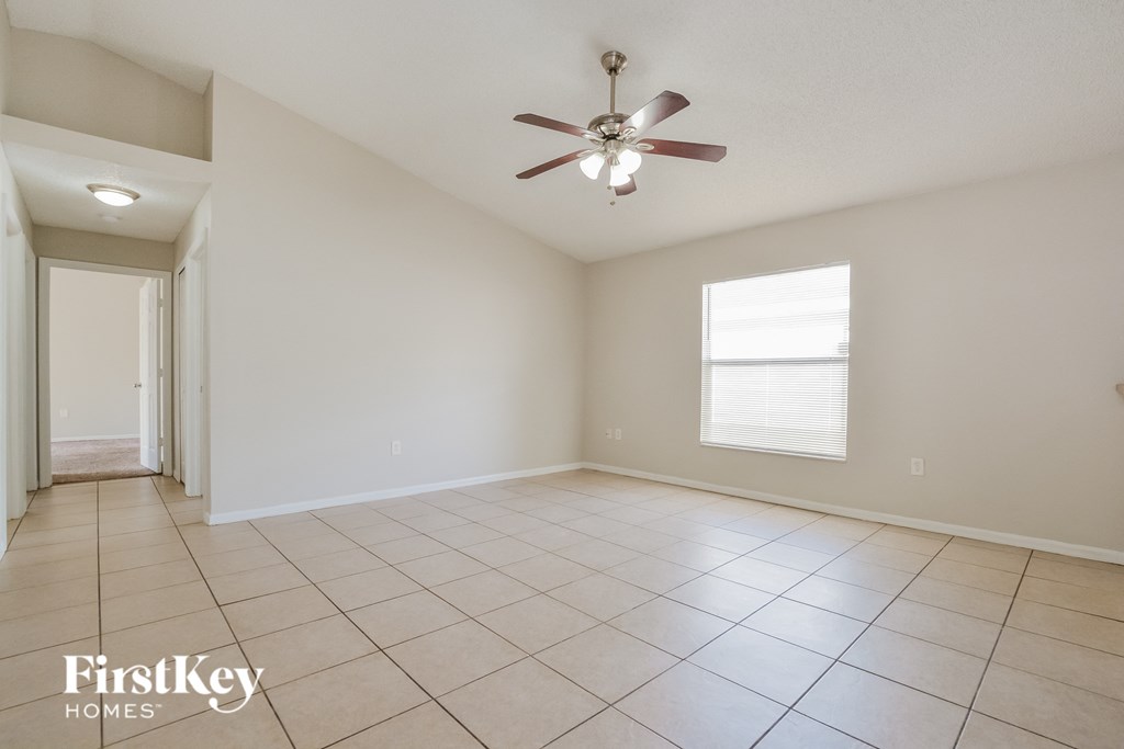 A spacious room with a ceiling fan and a window with blinds.