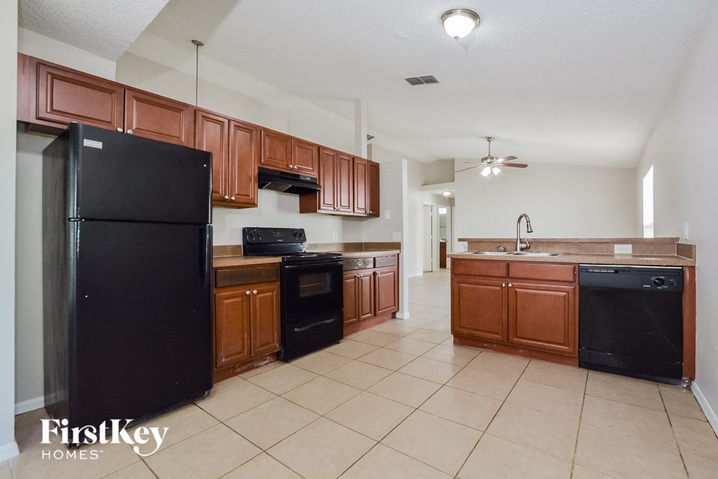 A kitchen with brown cabinets and a black fridge.