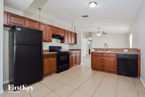 A kitchen with brown cabinets and a black fridge.