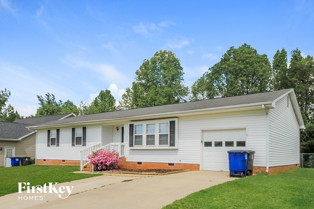 a white house with a blue trash can in front of it