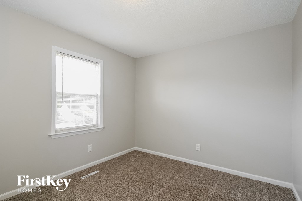 a bedroom with a window and a carpeted floor