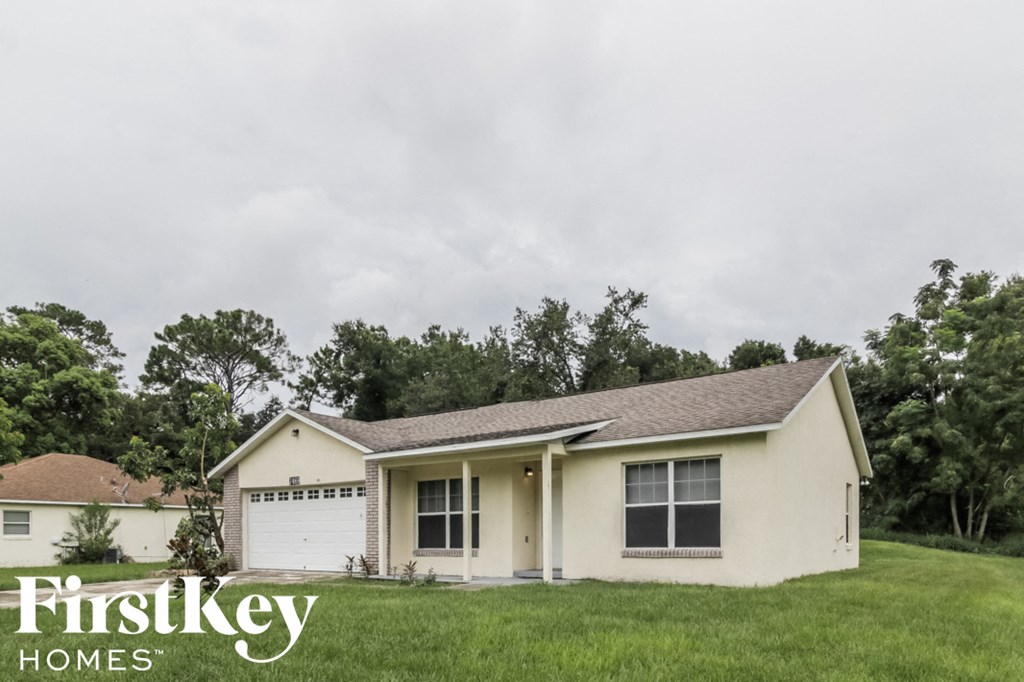 a small white house with a yard and a garage