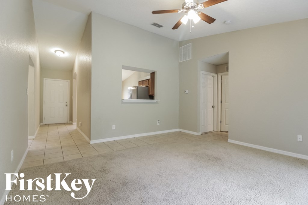 an empty living room with a ceiling fan and a tile floor