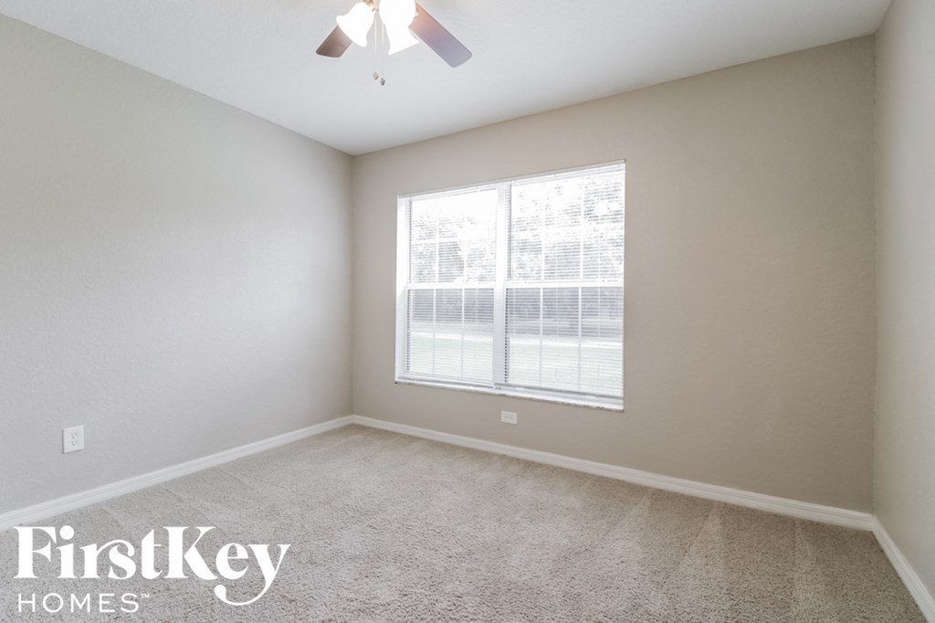 a bedroom with a large window and a carpeted floor