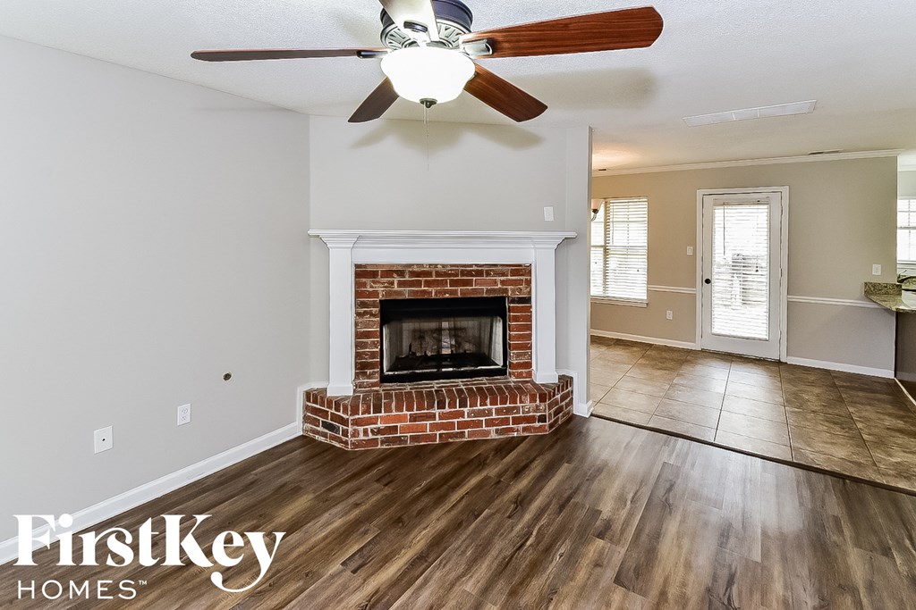 a living room with a brick fireplace and a ceiling fan