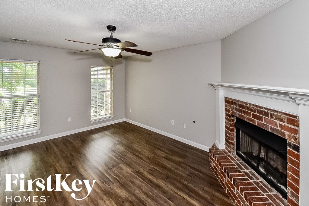 a living room with a brick fireplace and a ceiling fan