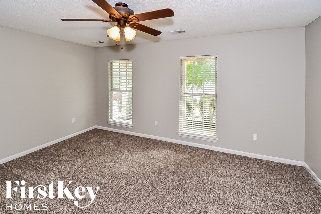 the master bedroom has a carpeted floor and a ceiling fan
