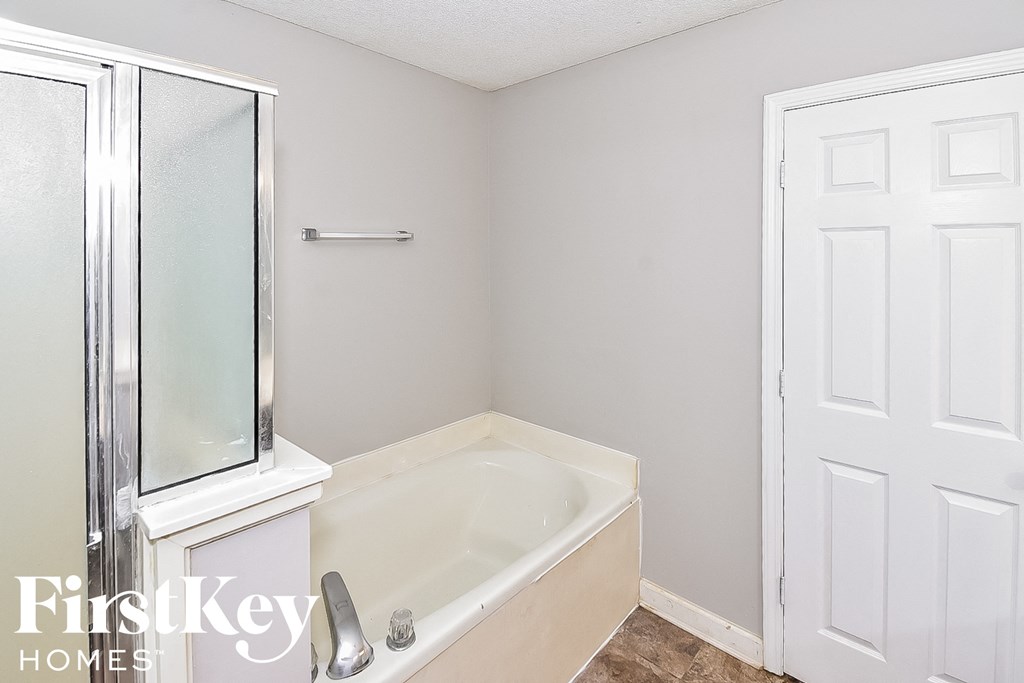 a bathroom with a bath tub and a shower and a white door