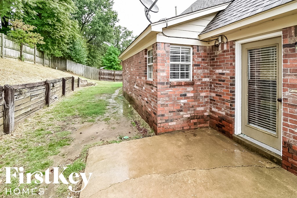 the backyard of a brick house with a driveway and a brick wall